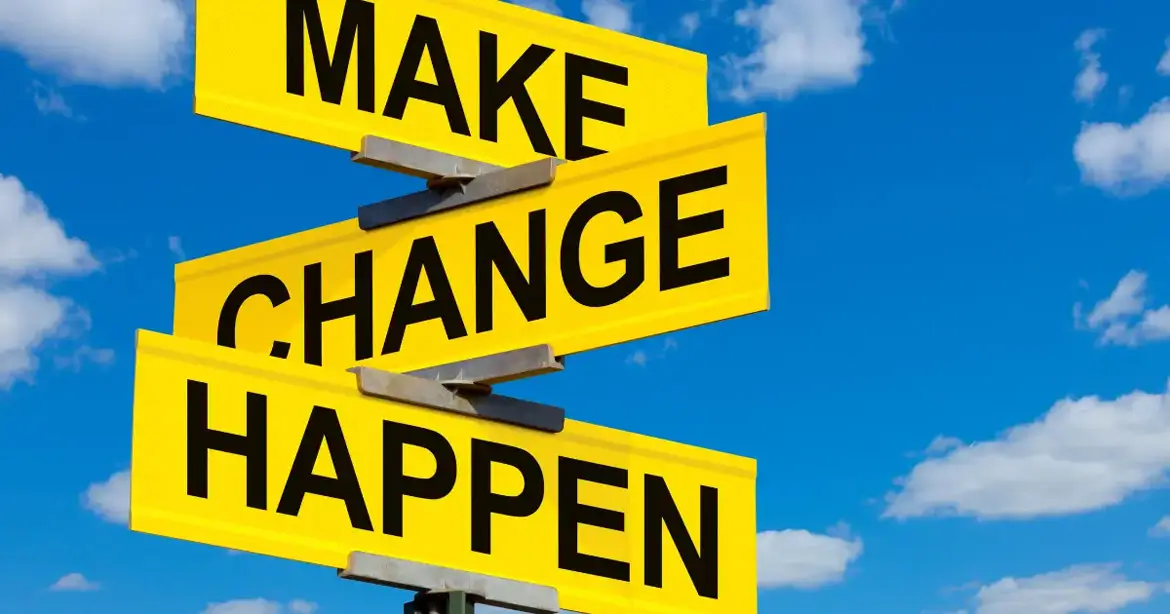 Yellow road signs against a blue sky with clouds, displaying the words "MAKE," "CHANGE," and "HAPPEN."